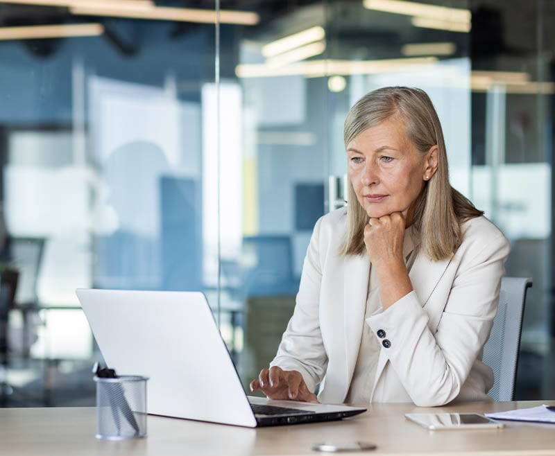 A woman looking thoughtfully at her computer.
